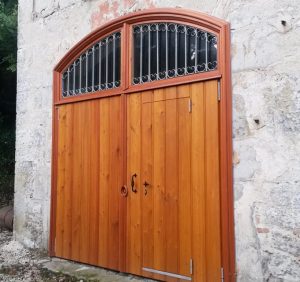 Porte massive en Mélèze avec traverse cintrée et grille forgée